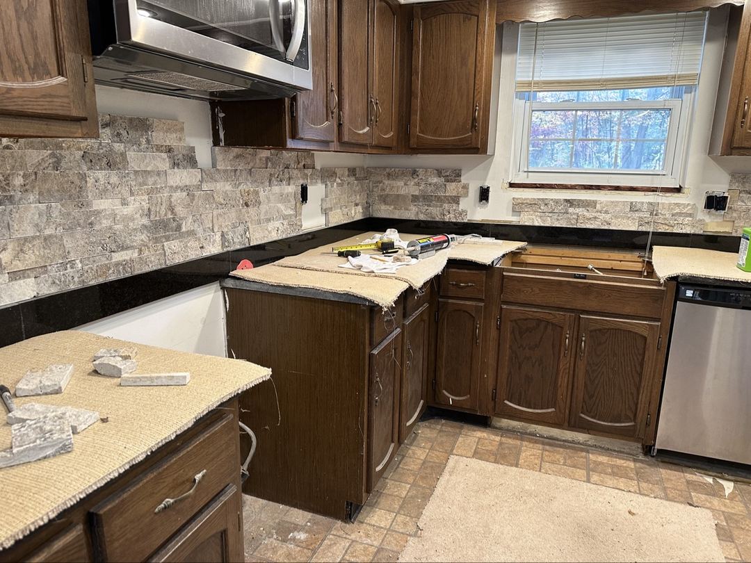 Wide view of the stacked-stone backsplash in progress across the kitchen
