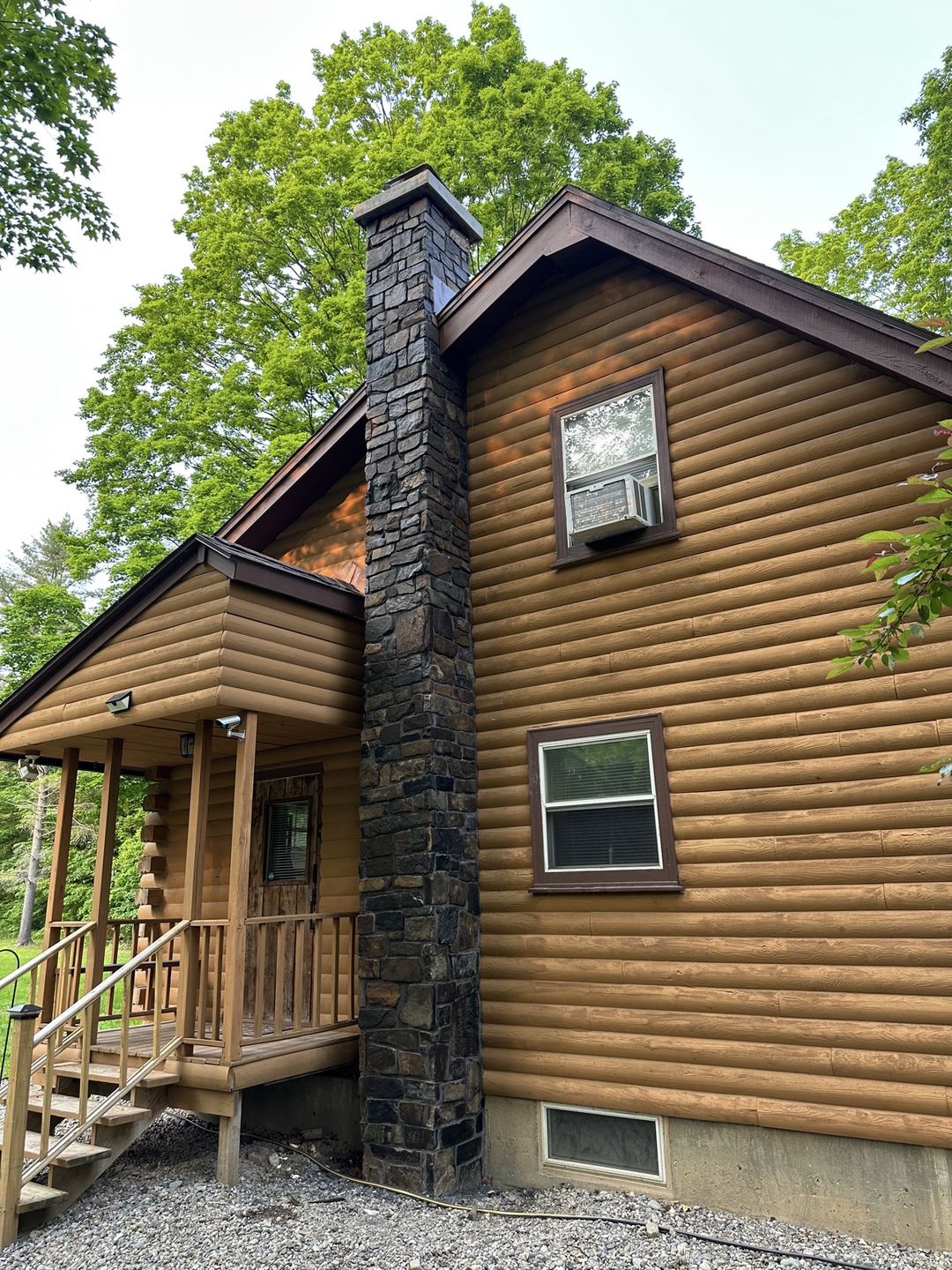 After: the cabin chimney fully faced in stone, seen from the porch side