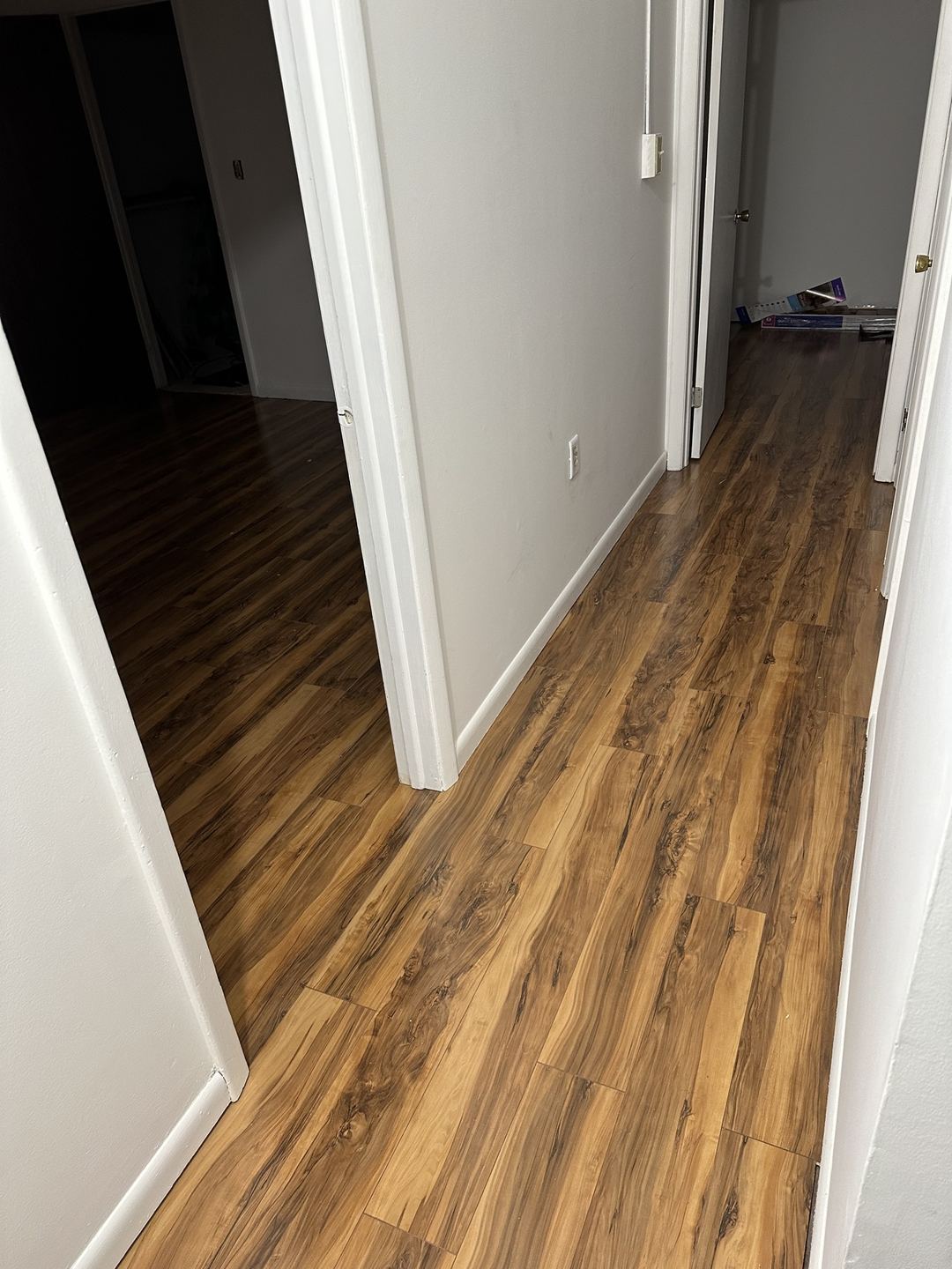 Finished plank flooring running through a hallway and adjoining rooms