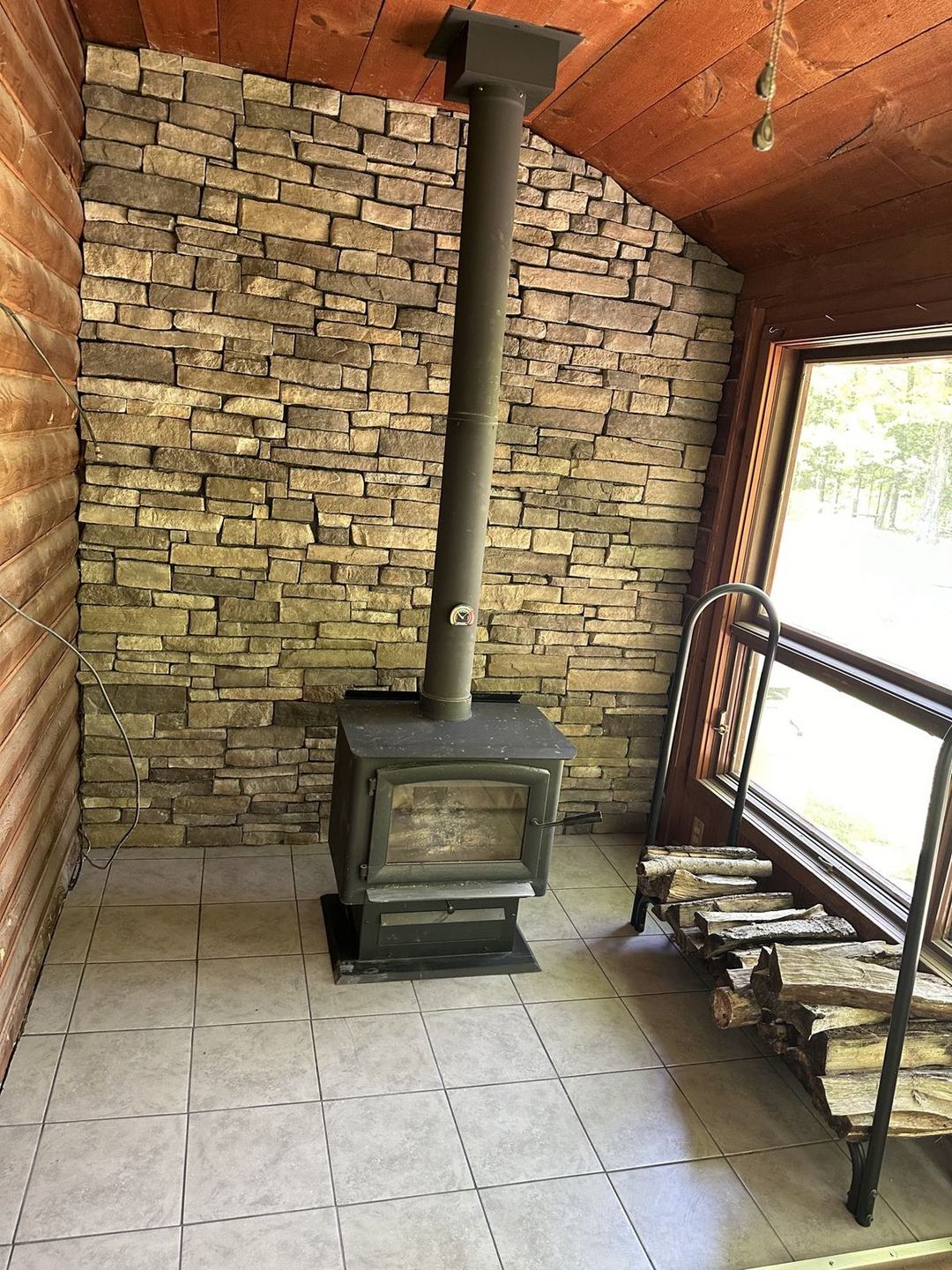 Finished interior stone veneer wall behind a wood stove
