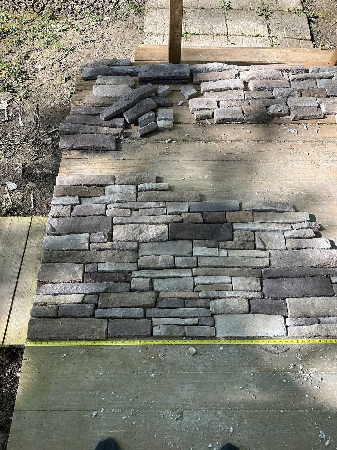 Stone veneer pieces dry-fit and laid out with a tape measure before installation